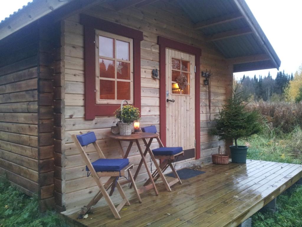 cabina con mesa y sillas en la cubierta en Cabin on Husky Farm, en Strömsund