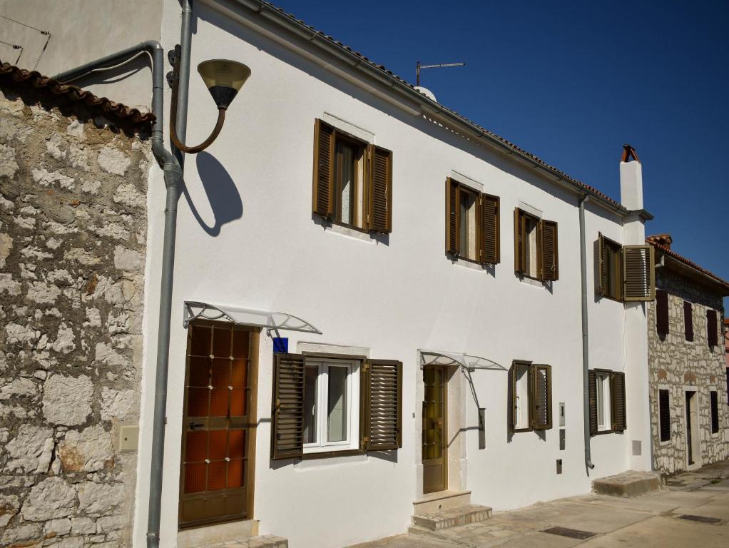 a white building with brown shuttered windows at Holiday Apartment Vrsar in Vrsar