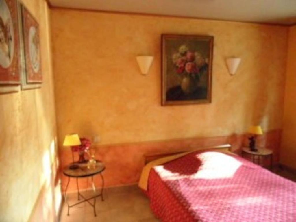 a bedroom with a red bed and a painting on the wall at L'OLIVERAIE EN PROVENCE in Lambesc