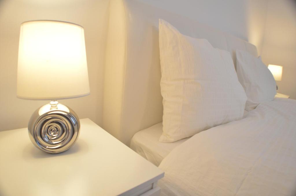 łóżko z białą poduszką i lampą na stole w obiekcie Central GREEN HOUSE w Bukareszcie