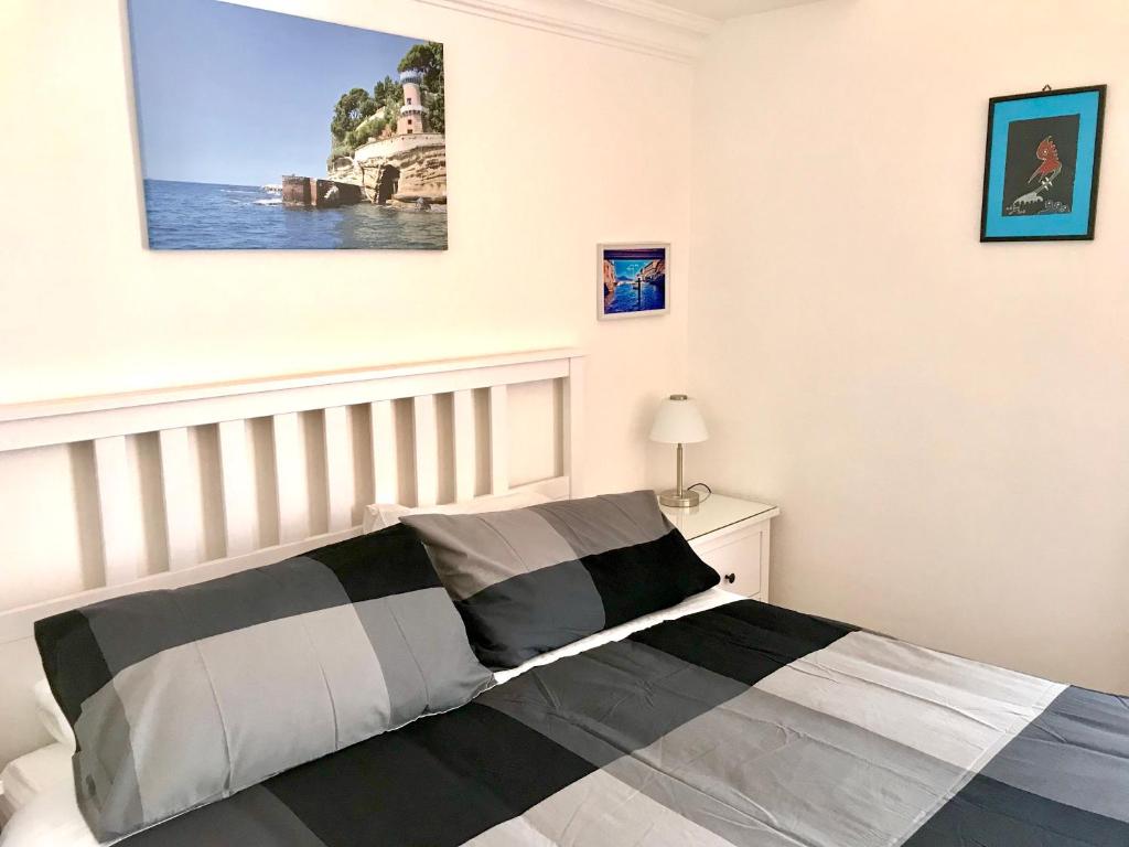 una camera da letto con un letto bianco e nero con una foto sul muro di Casa Annamaria a Napoli
