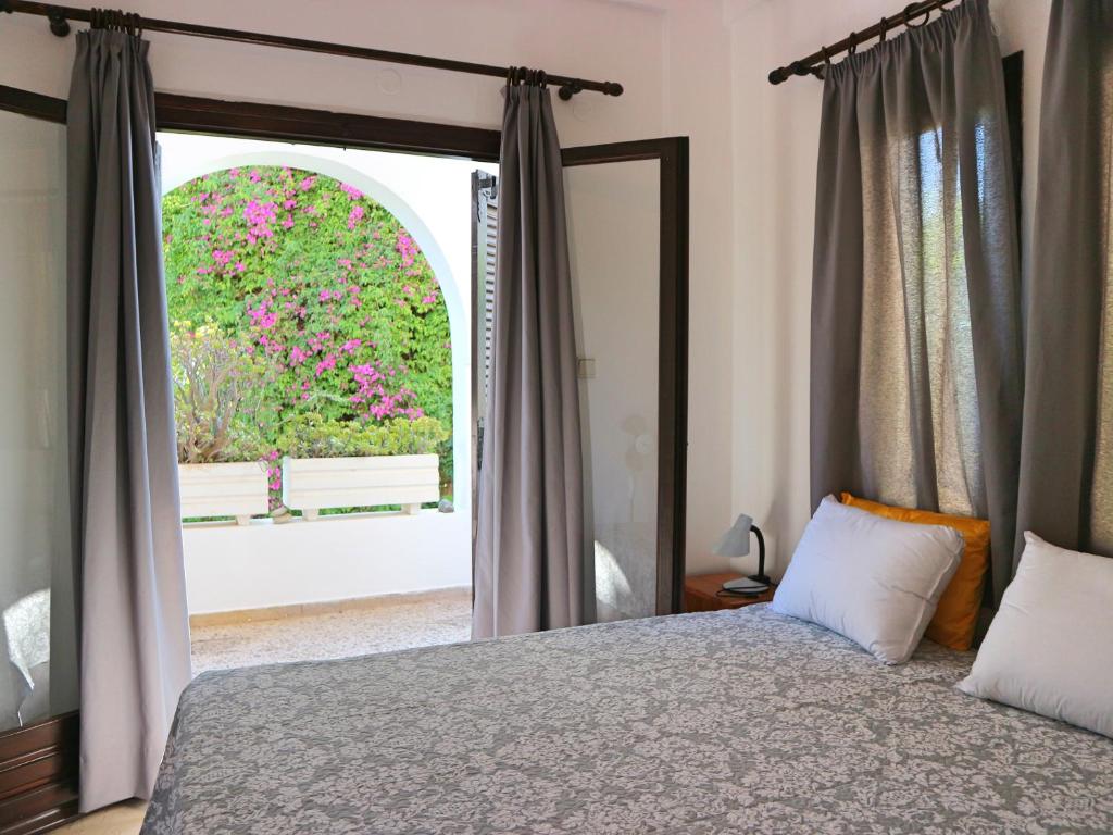 a bedroom with a bed and a window with pink flowers at Oliaria Apartments in Platanias