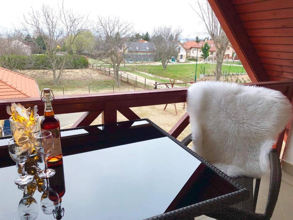 a table with a bottle of wine and glasses on a balcony at Rege apartman in Alsóörs