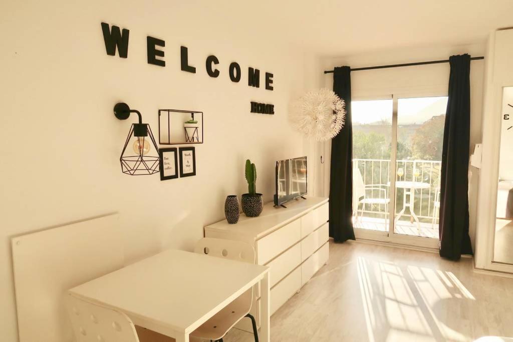 Habitación blanca con mesa y cartel de bienvenida en la pared en Minerva Sea View Apartment, en Benalmádena