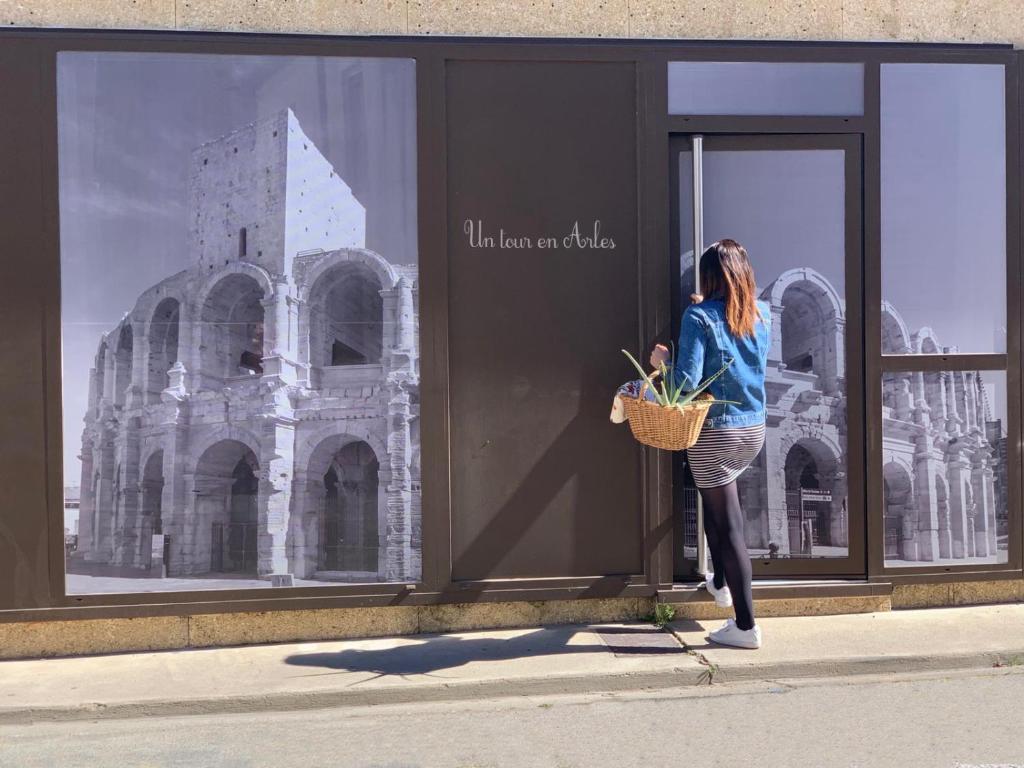 a woman standing in front of a window looking at a building at Un tour en Arles in Arles