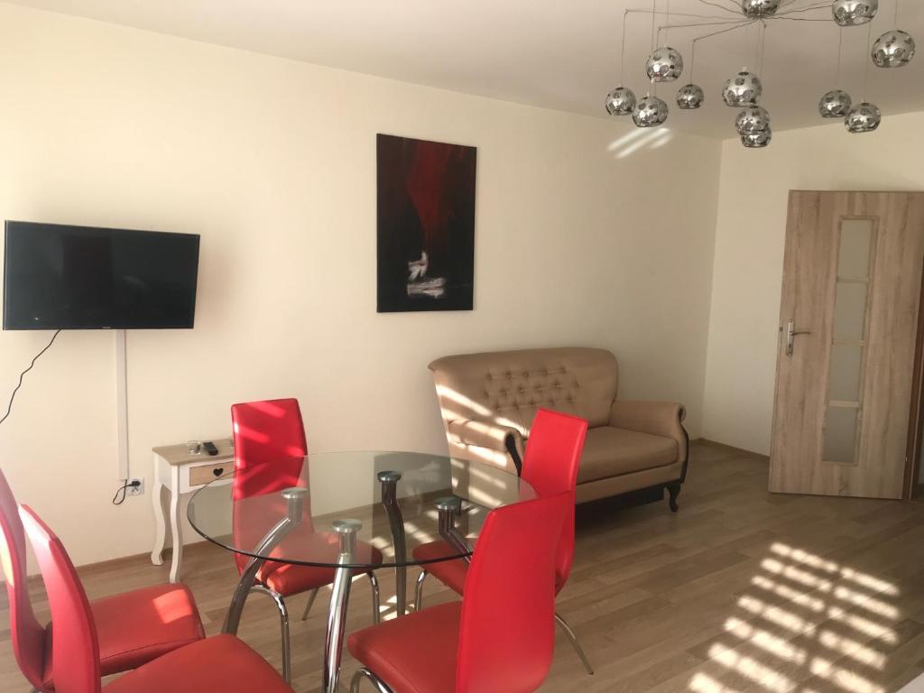 a living room with a glass table and red chairs at Apartament Rodzinny S8 in Kalisz