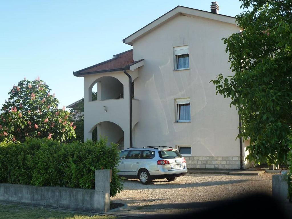a car parked in front of a white house at Apartment Ivan-Experience 2 Bedrooms in Ljubuški