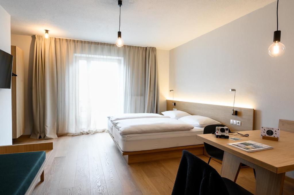 ein Hotelzimmer mit einem Bett, einem Schreibtisch und einem Fenster in der Unterkunft Calva B&B Apartments in Mals im Vinschgau