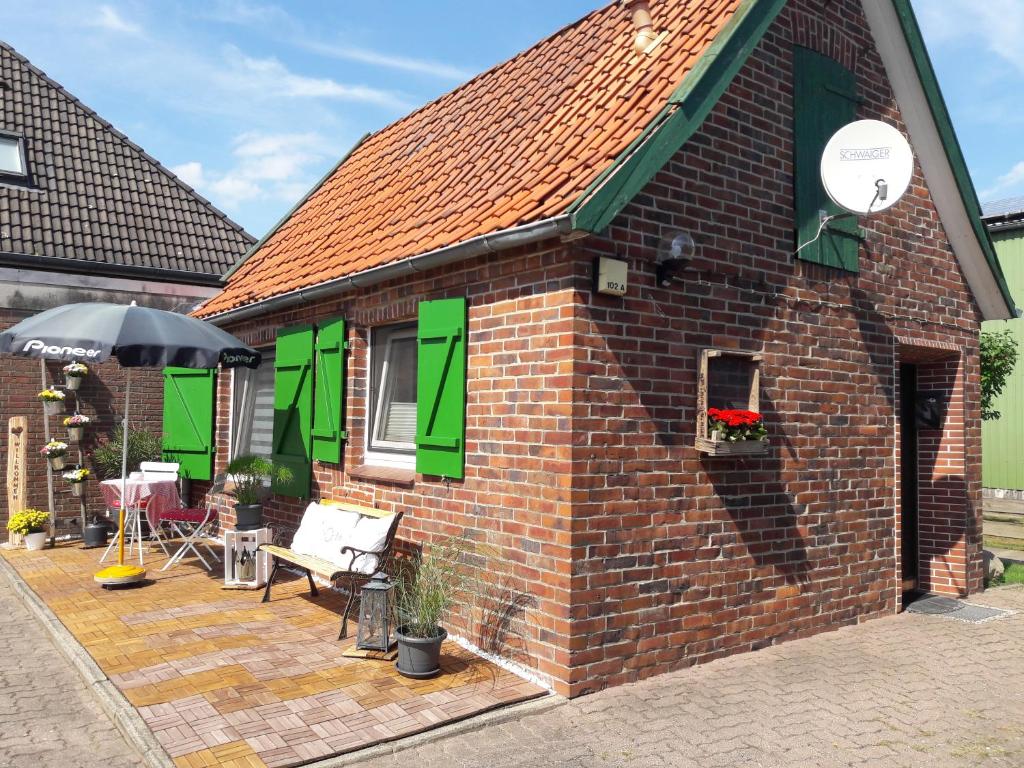 een bakstenen gebouw met groene luiken en een patio bij Gemütliches Häuschen im Alten Land in Jork