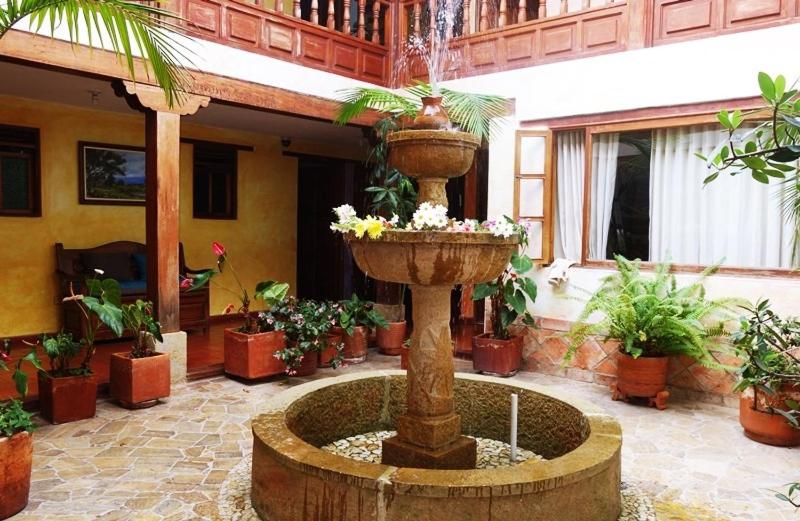 a fountain in the middle of a courtyard with potted plants at Hotel Sol de la Villa in Villa de Leyva