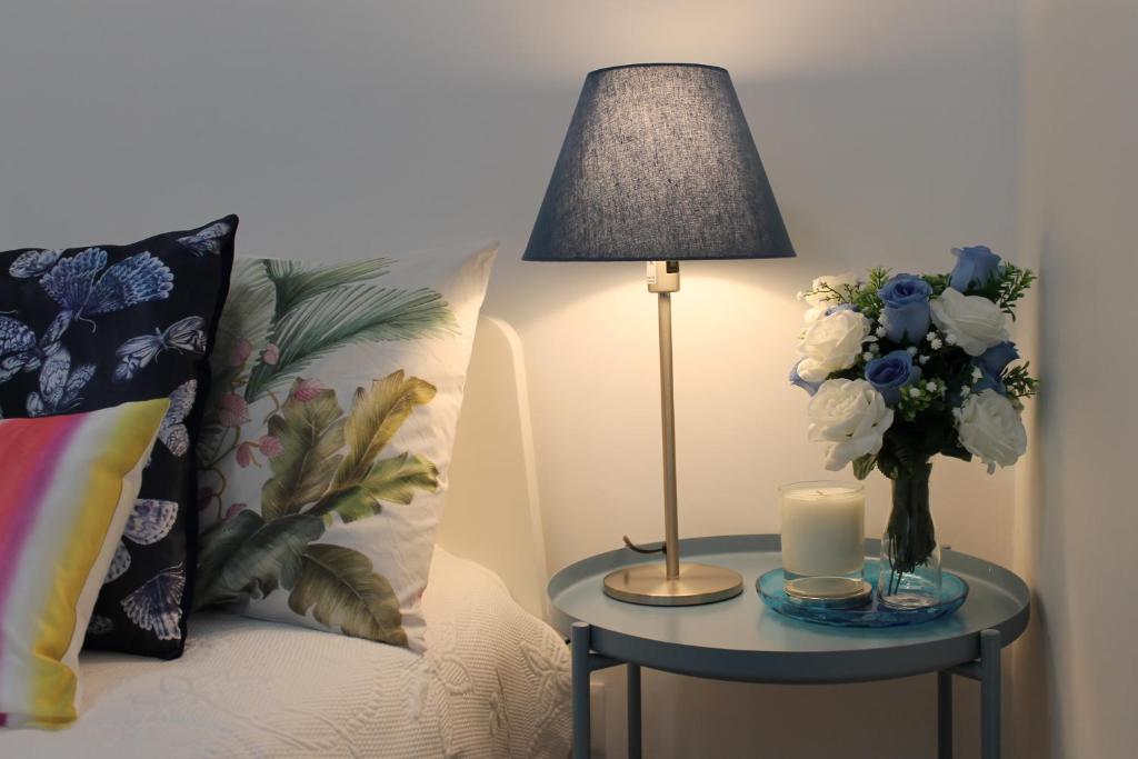 a table with a lamp and a vase of flowers on a bed at Madre Deus Guest House in Lisbon