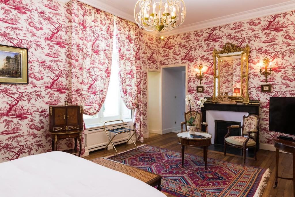 - une chambre avec du papier peint floral rose et une cheminée dans l'établissement Château de Beauvais, à Azay-sur-Cher