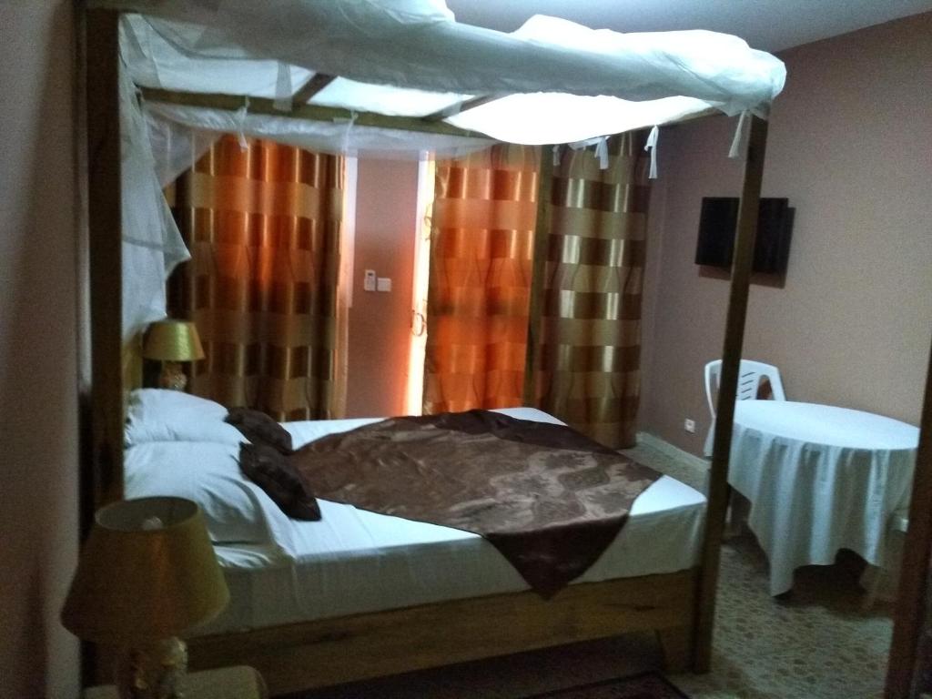 1 dormitorio con cama con dosel y mesa en Africa 6 Plage, en Somone