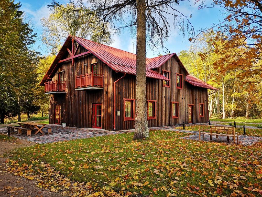 a large wooden barn with a red roof at Svilpaunieki in Lūznava