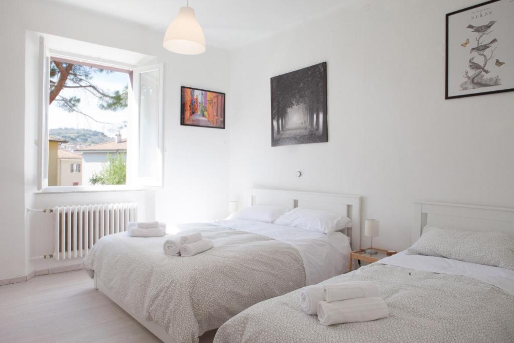 Dos camas en una habitación blanca con ventana. en Cleo Giglio, en Ancona