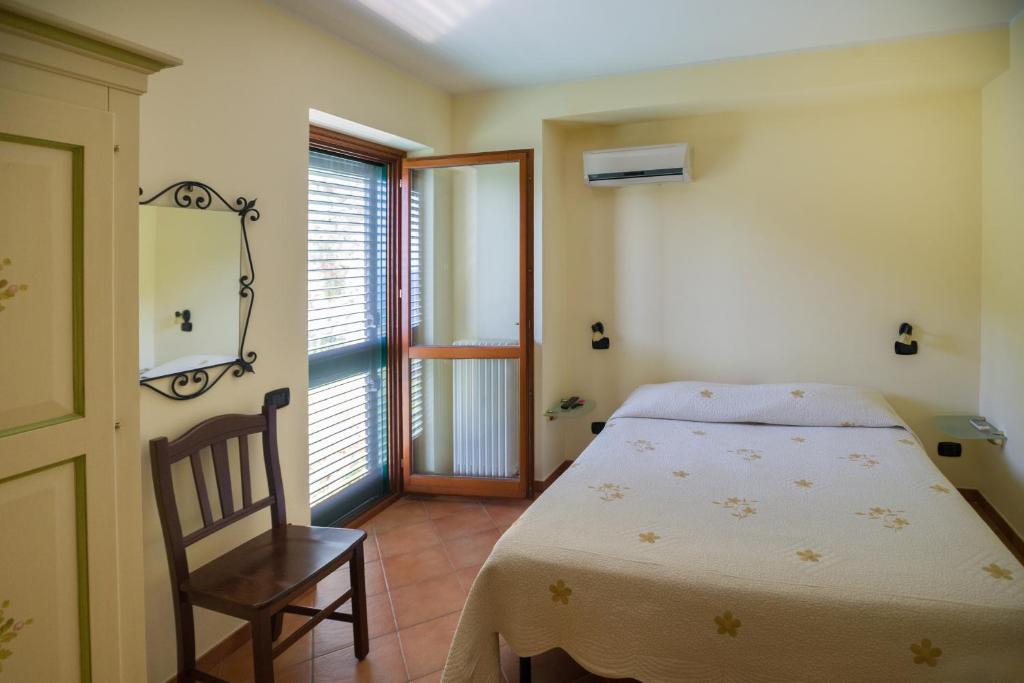 a bedroom with a bed and a chair and a window at Il Glicine in Cetara