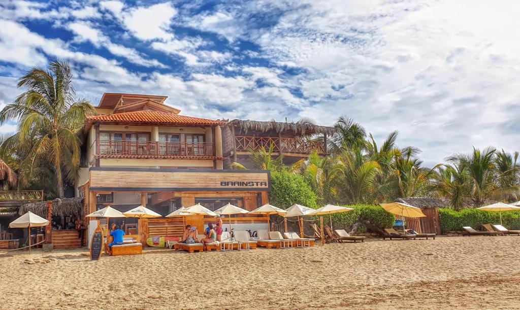 un edificio en la playa con mesas y sombrillas en Don Giovanni Mancora en Máncora