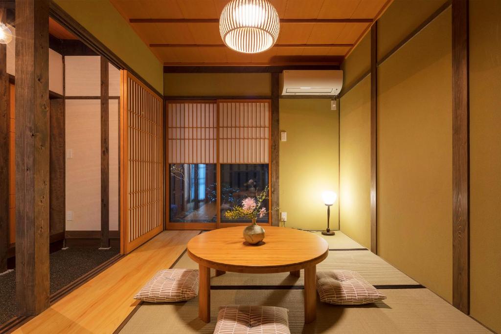 een eetkamer met een tafel en een lamp bij Yoshimigura Machiya House in Kyoto