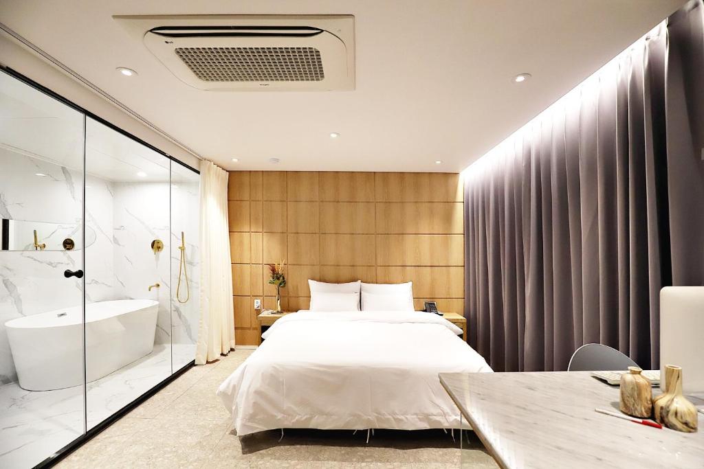 Biennale Hotel في غوانغجو: غرفة نوم بسرير وحوض استحمام ومغسلة