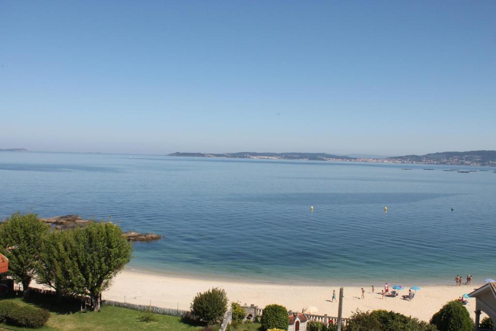 un gran cuerpo de agua con gente en una playa en Hotel Alda Bueumar, en Bueu