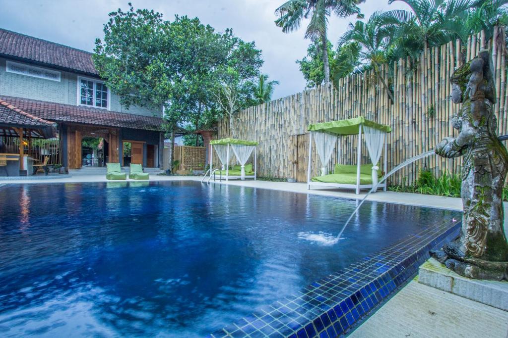 a swimming pool with a fountain in a yard at A4K Sanggingan Villa in Ubud