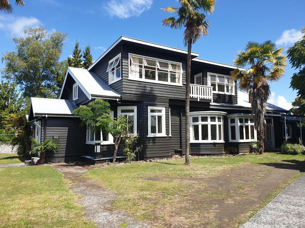a black house with palm trees in front of it at 21morero in Taumarunui