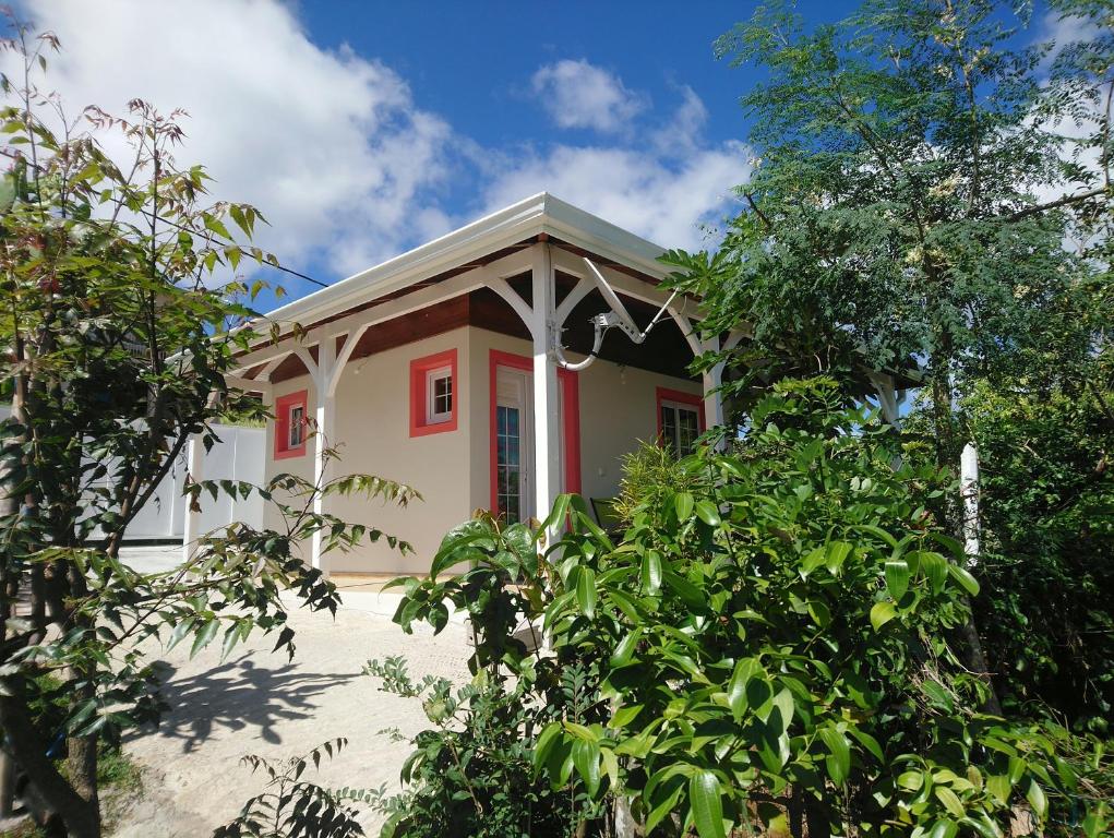 une maison avec une porte rouge et des arbres dans l'établissement Grenadier, à La Trinité