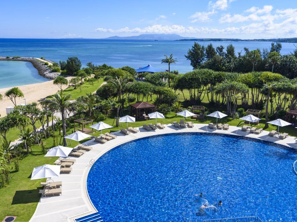 an aerial view of a resort pool with chairs and umbrellas at Sheraton Okinawa Sunmarina Resort in Onna