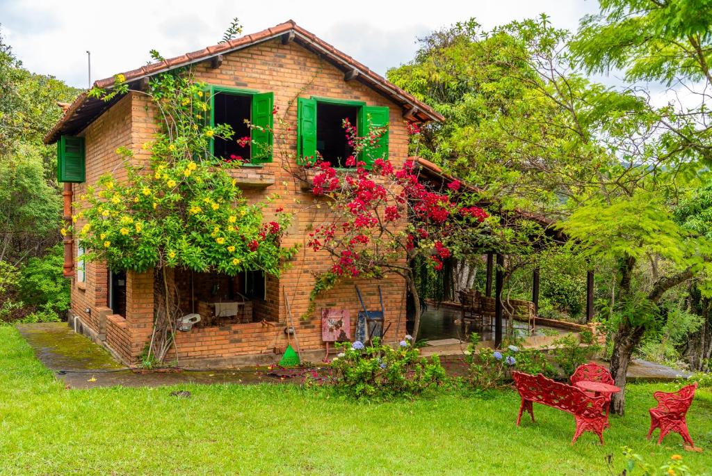 una casa de ladrillo con sillas rojas delante de ella en Charmoso Refúgio nas Montanhas com 8 Cachoeiras Privativas, en Rio Acima