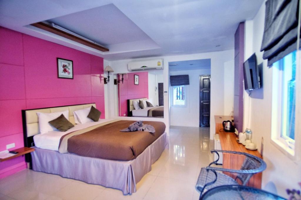 ラマイにあるアット ラマイ リゾートのピンクの壁のベッドルーム1室(大型ベッド1台付)