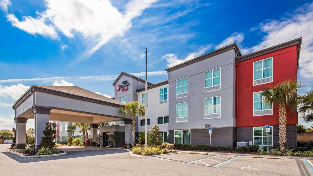 un bâtiment d'hôtel avec des palmiers dans un parking dans l'établissement Best Western Plus Chain of Lakes Inn & Suites, à Leesburg