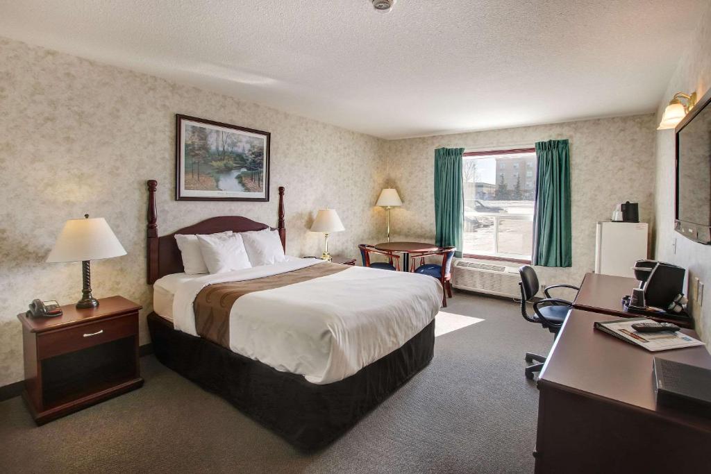 Ramada by Wyndham Nisku Edmonton Airport في نيسكو: غرفة في الفندق مع سرير ومكتب