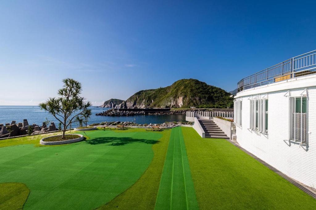 a green lawn next to a building and the ocean at Brighthouse in Suao