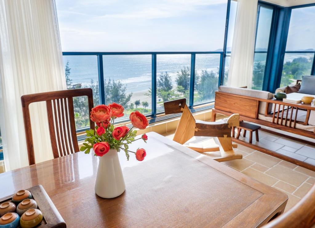 un jarrón con flores en una mesa en una habitación en Listen to the Sea Apartment en Huidong