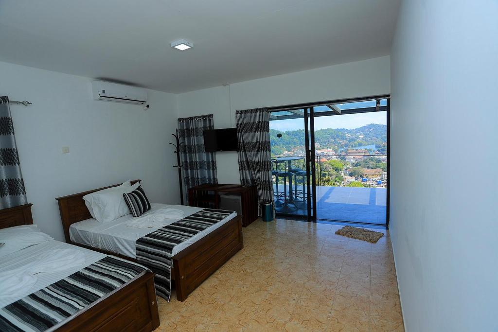 a hotel room with two beds and a balcony at Vendol Sky Resort in Kandy