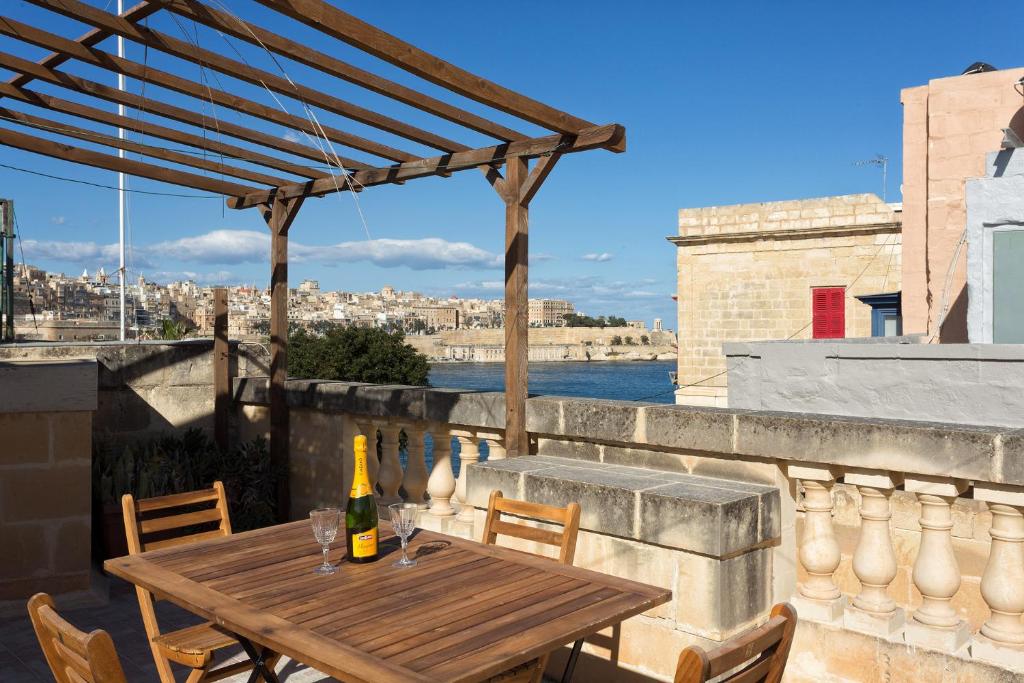 a wooden table on a balcony with a bottle of wine at Traditional Maltese Townhouse, Roof Terrace and Views in Senglea