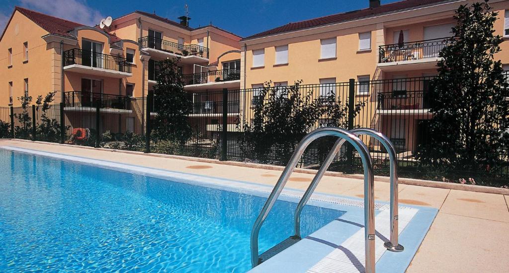 a swimming pool in front of some apartment buildings at Domaine de Bussy in Bussy-Saint-Georges