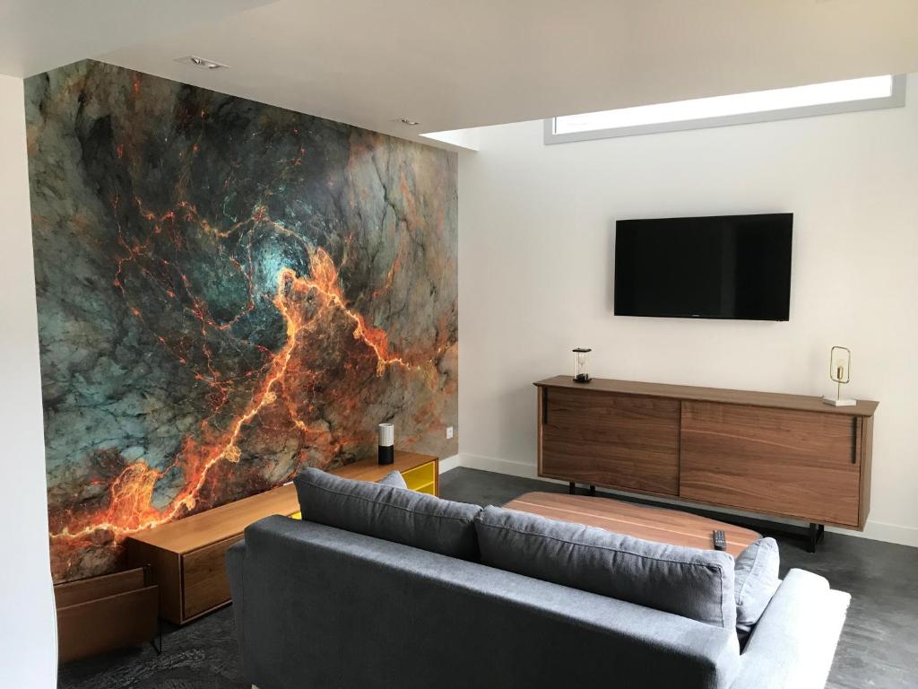 a living room with a couch and a tv on a wall at Résidence Solférino in Laval