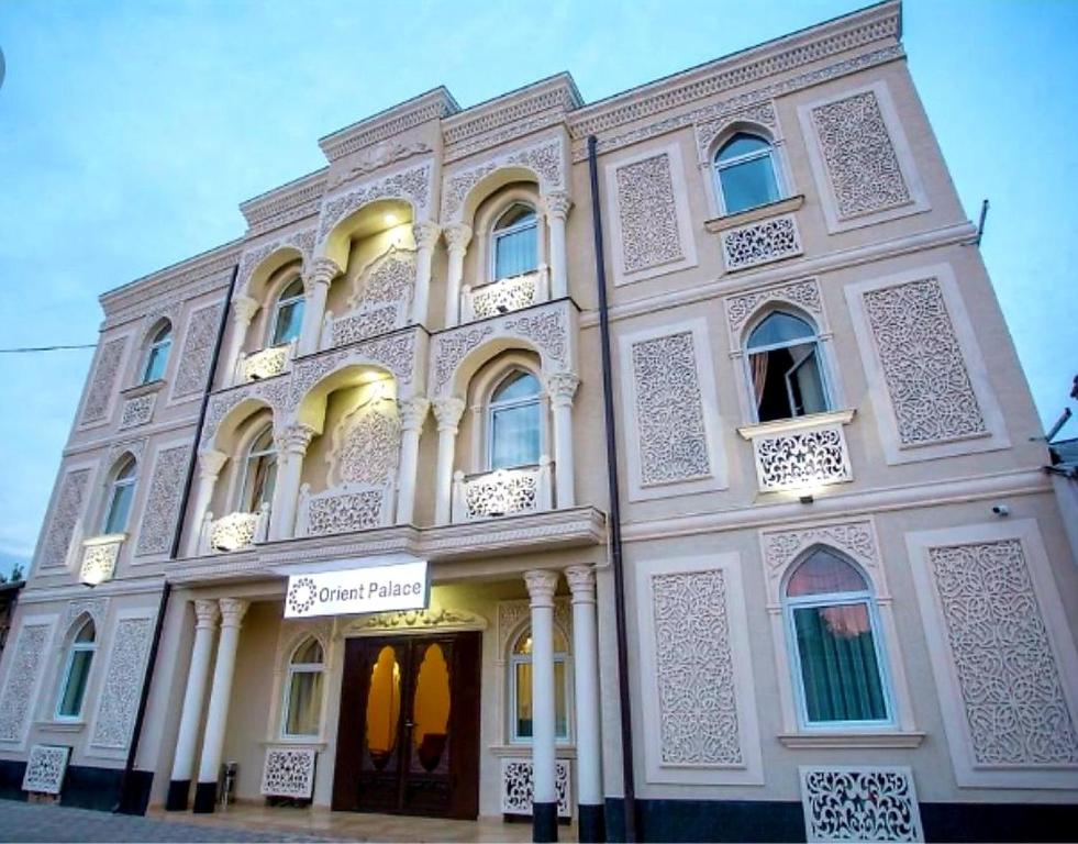 un gran edificio blanco con un cartel. en Orient Palace, en Tashkent