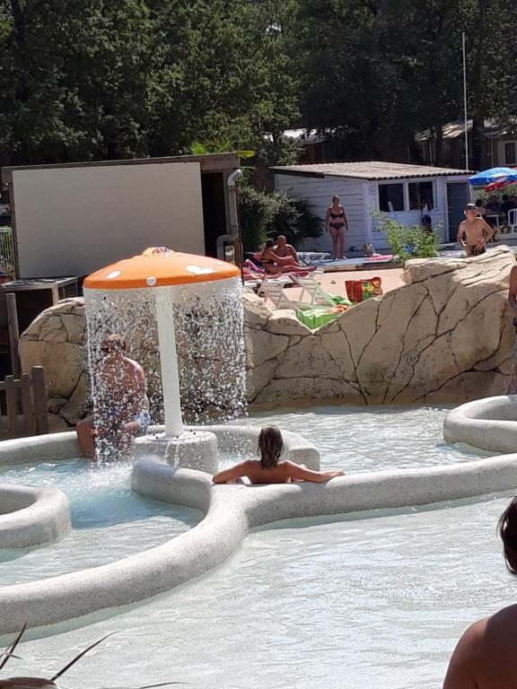 un par de personas en una piscina con sombrilla en Mobil Home Sainte Baume en Nans-les-Pins