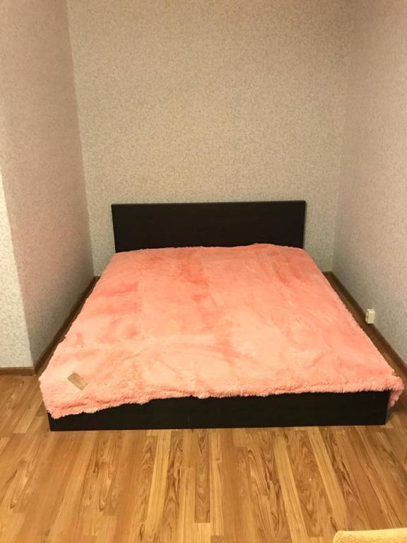 a bed with a orange blanket on top of a wooden floor at Apartment G-Kvartal Planernaya 7k4 in Moscow