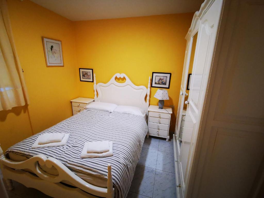 a bedroom with a white bed with yellow walls at Apartamento Candil in Puerto Naos