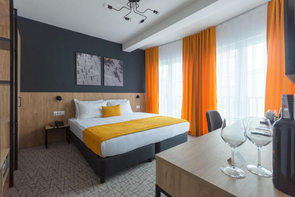 um quarto de hotel com uma cama e dois copos de vinho em City Inn em Pristina