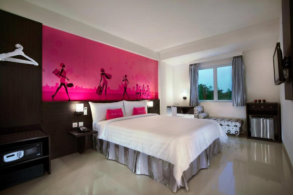 1 dormitorio con 1 cama grande y pared de color rosa en favehotel Kelapa Gading en Yakarta
