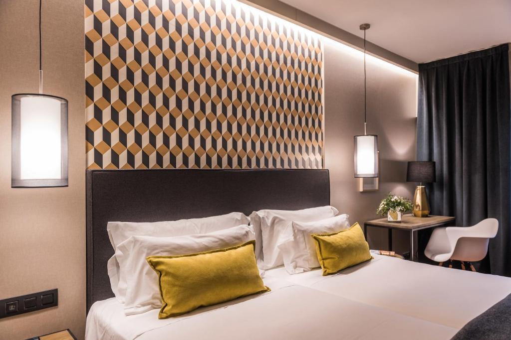ein Schlafzimmer mit einem großen Bett mit zwei gelben Kissen in der Unterkunft Up Rooms Vic Hotel in Vic