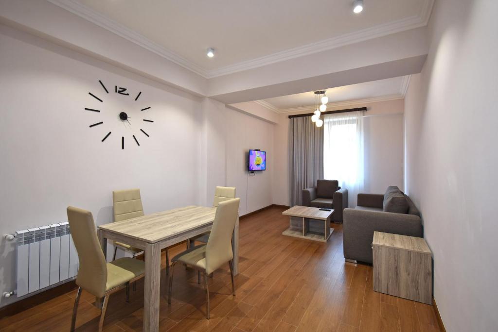 a living room with a table and a clock on the wall at Luxury apartments just near Republic Square in Yerevan
