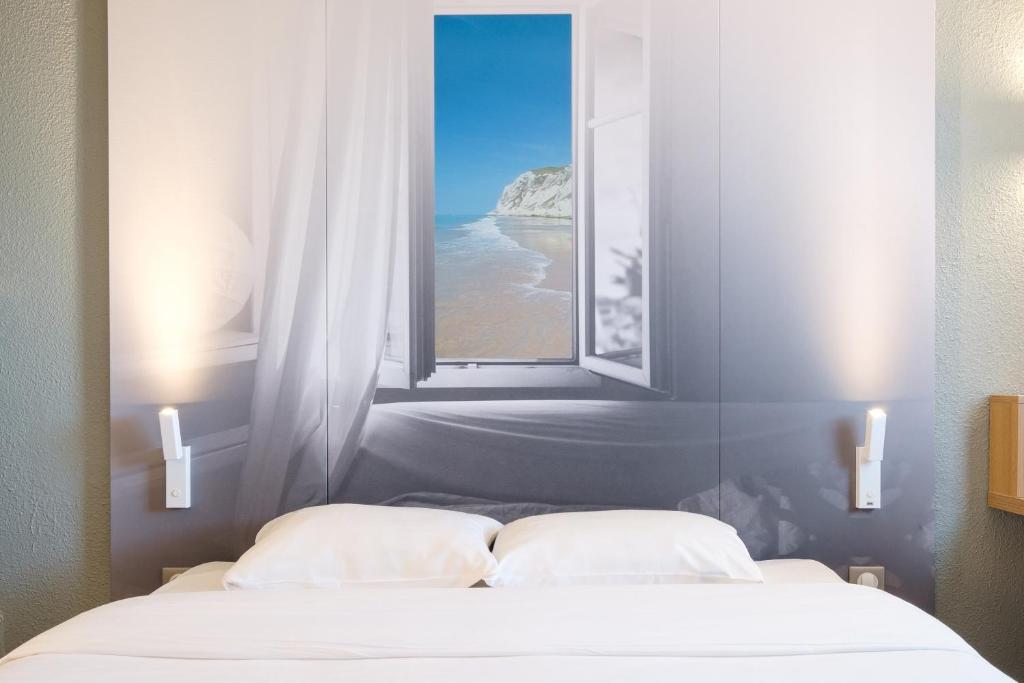 a bed with a window with a view of the ocean at B&B HOTEL Calais Centre St Pierre in Calais