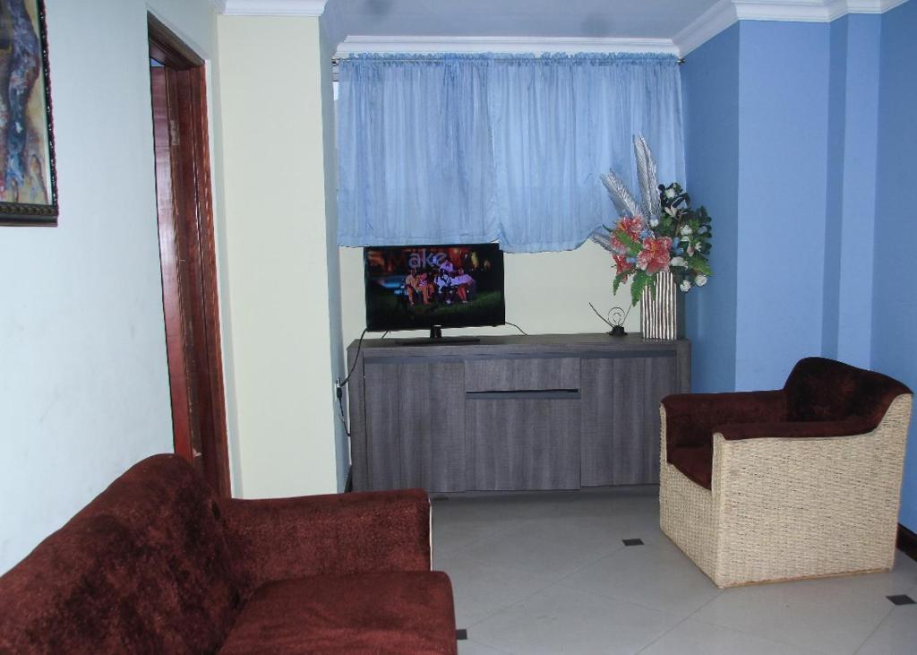 a living room with two chairs and a television at Ridge Over Suite in Accra
