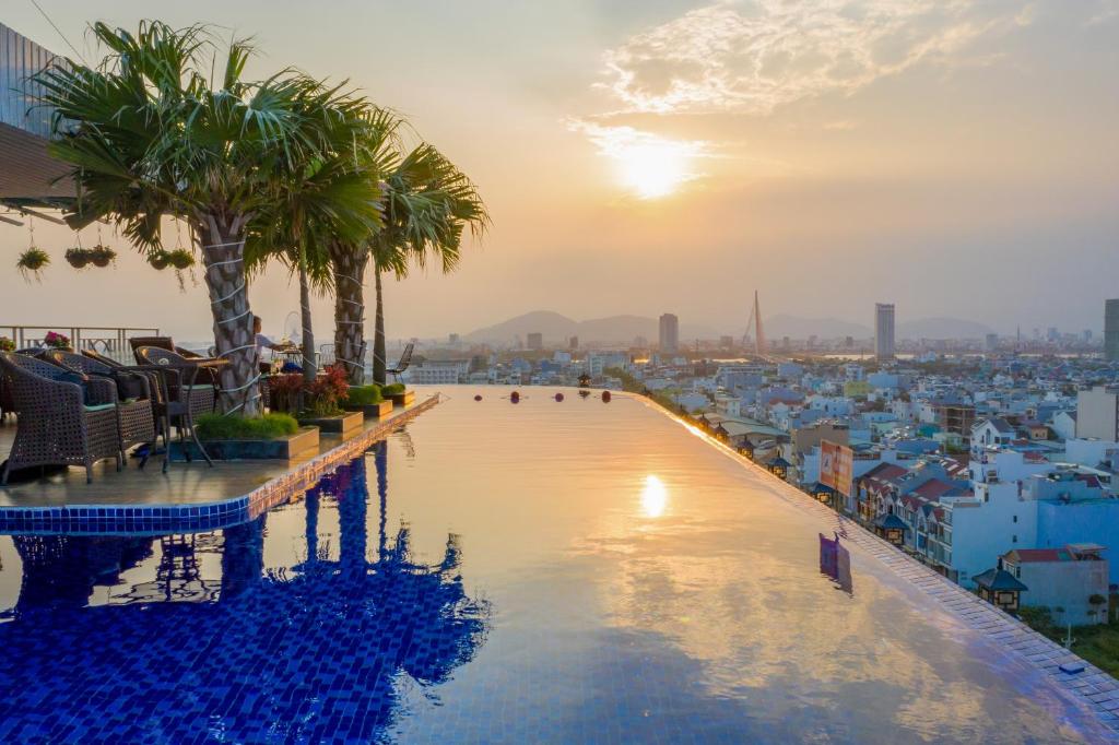 a swimming pool on the roof of a building with a sunset at SEA QUEEN Hotel in Da Nang