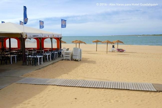 サンルーカル・デ・バラメダにあるPlaya de Las Piletasのビーチにはテーブルと椅子、パラソルが備わります。